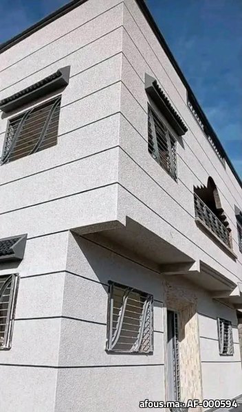 Façade d'angle à crépi gris clair projeté — Ksar El Kébir